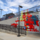 400 feet of mandarin, teal, kiwi & gray tile mosaics in varying sizes with bold, linear architectural patterns on the walking ramps of both sides of Charlotte’s 25th St Station light rail platform. Handrails above each mosaic are powder coated in corresponding colors.