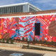 20’ h x 80’ w hand & spray-painted energetic, abstract mural with overlapping planes of reds, blues & oranges. Architectural lines in blues, black & white echo industrial buildings and towers of surroundings. Precise geometric shapes of exposed, unpainted red brick. Located on exterior wall of Goodyear Arts building in Charlotte’s Camp North End.