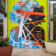 One-story, spray-painted mural of partially cool-colored & partially flesh-colored silhouette with voluminous curly hair. Open circles and other colorful organic shapes throughout. Plane broken by intersecting lines of varying widths, colors & lengths. Located on exterior wall of Charlotte’s Metropolitan complex, beside West Elm.