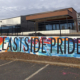 Detail of approx 950 sq ft mural covering multiple walls in Charlotte’s Eastway Crossing mall parking area. Eastside Pride painted in thin, black block letters over a busy, colorful mural of abstract geometric shapes & lines.