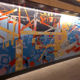 9' x 22' abstract, asymmetrical mural in 3 quadrants with linear design resembling deconstructed bridge trellis in upper left quadrant. Bold fire colors, cool blues, grays and black. In the elevator lobby of The Refinery, a luxury office building in Charlotte.